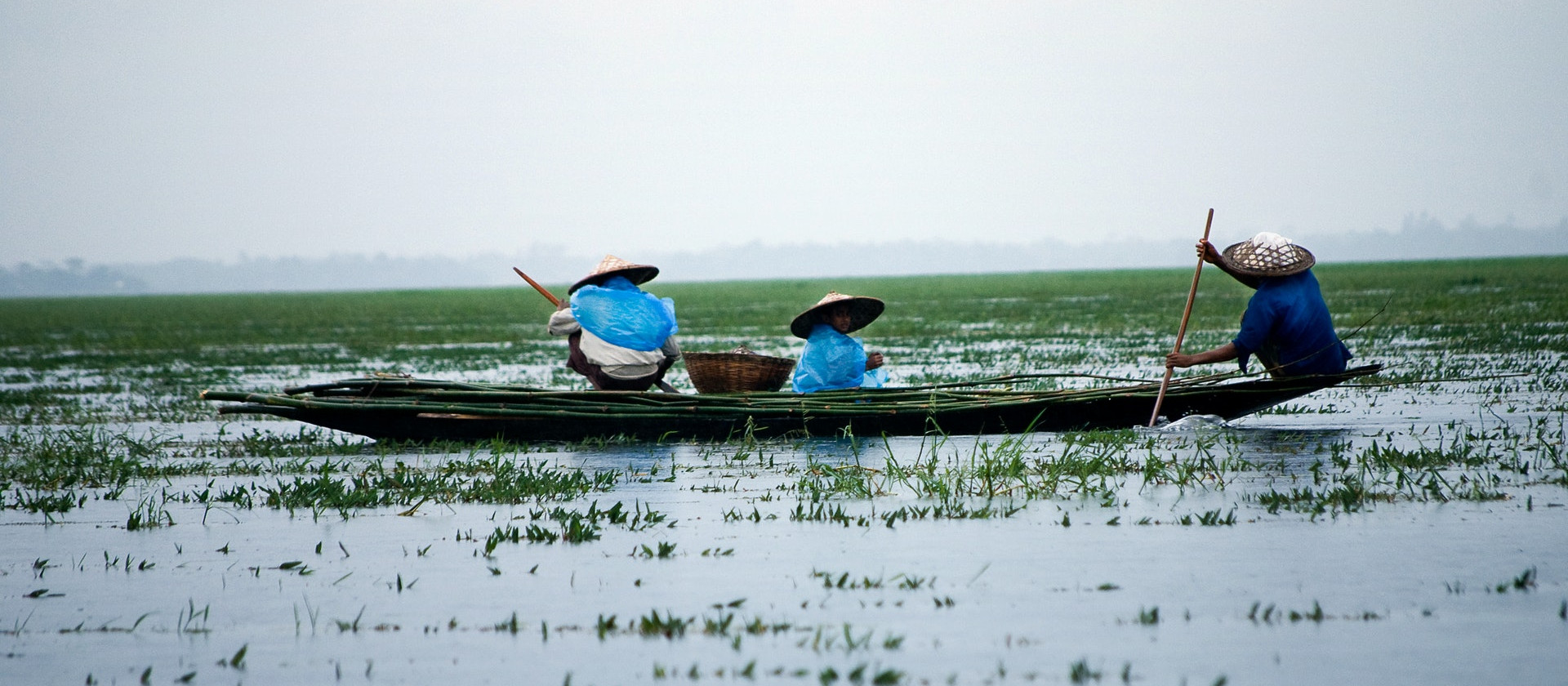 Three people in a boat at Sunamganj, Bangladesh