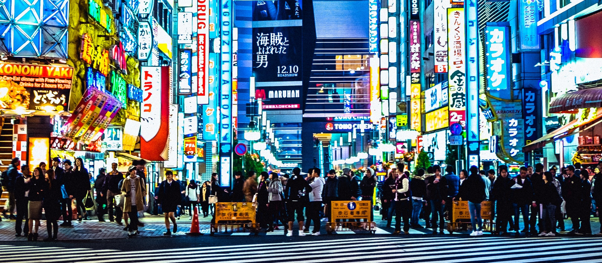 People crossing a busy street with shops at night in Japan