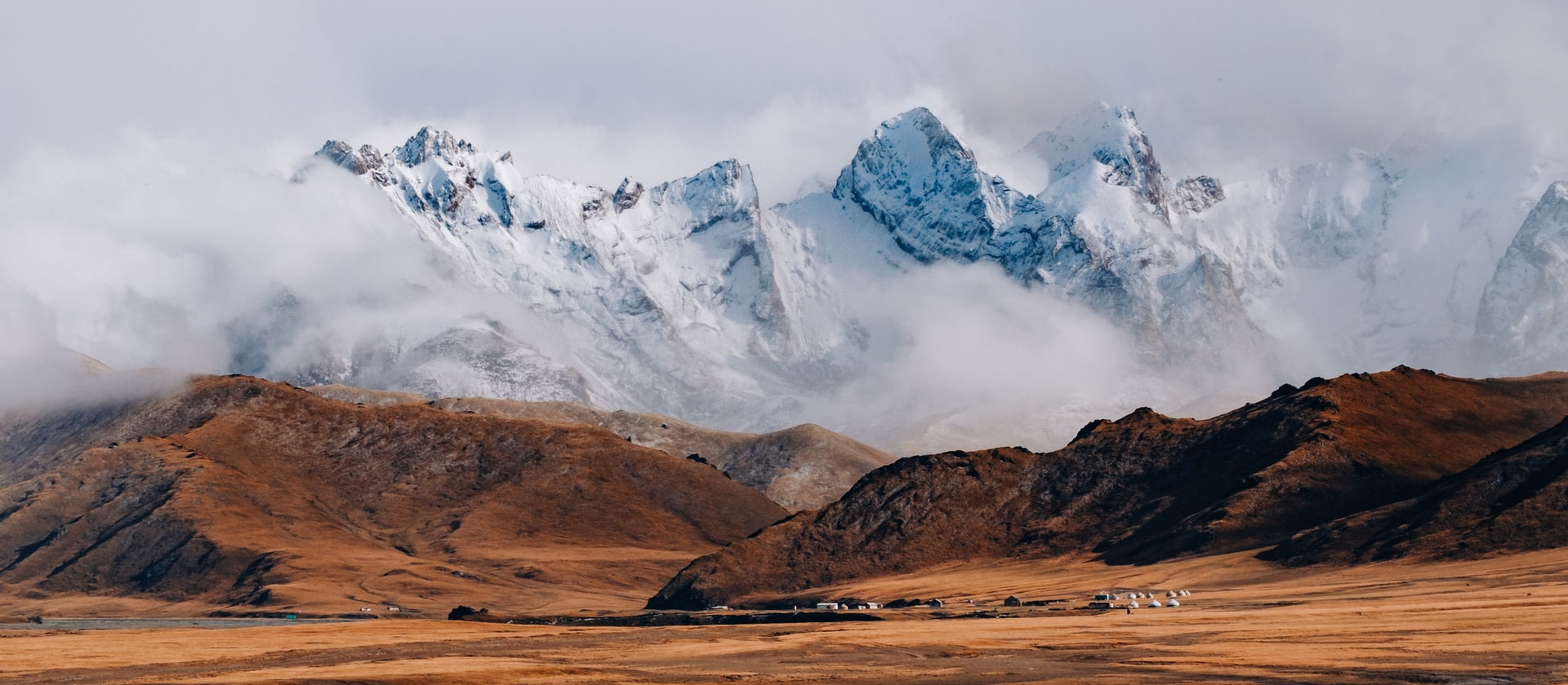 Group of yurts at the base of snow-covered mountains