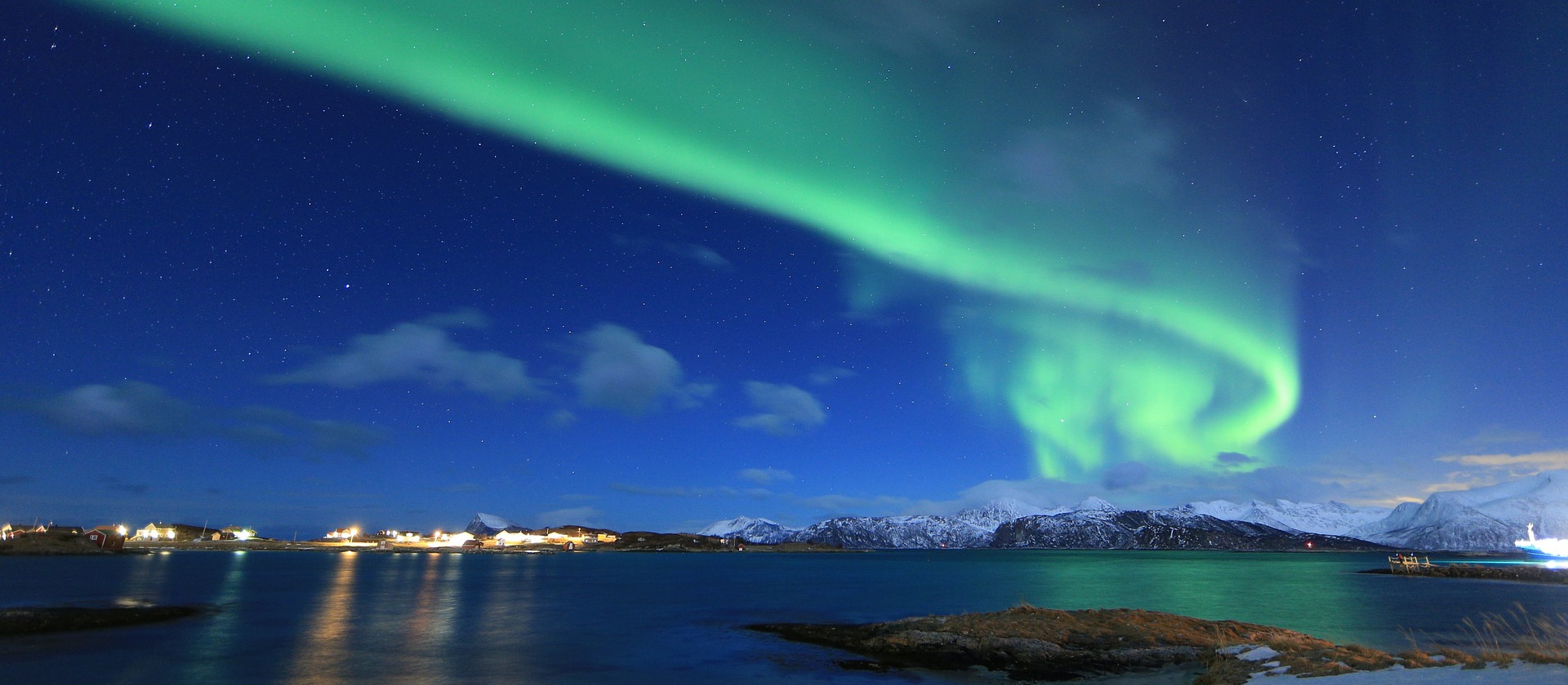 Aurora Borealis over sea and town in Norway