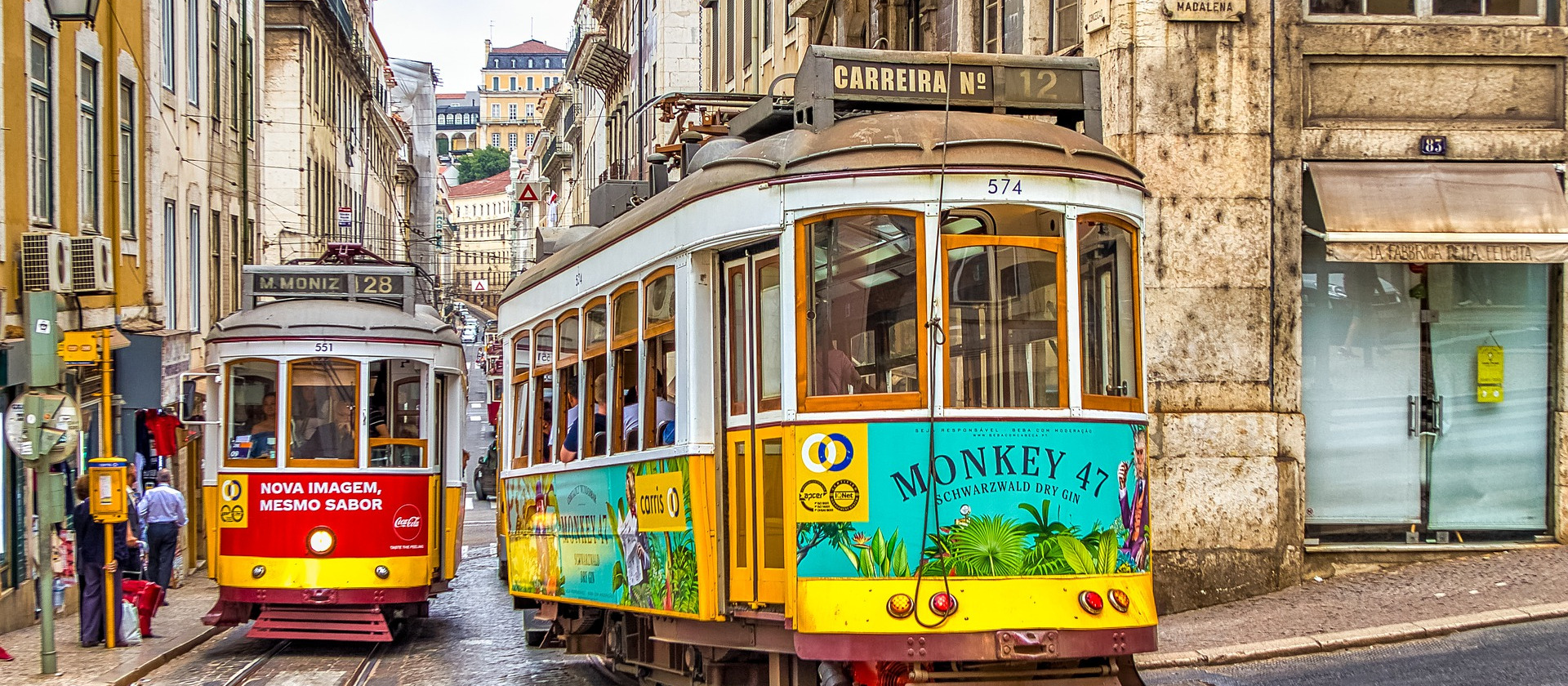 Two trams pass in a street in Lisbon, Portugal.