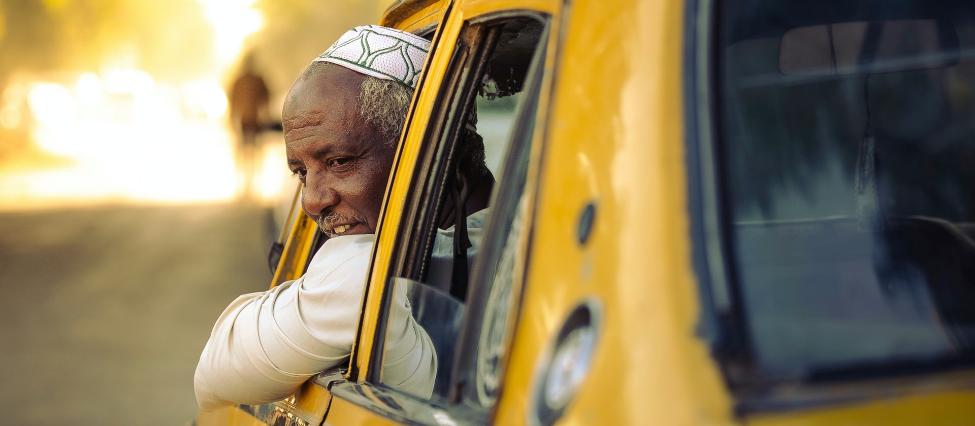 Man leaning out of driver's window of yellow car in Sudan